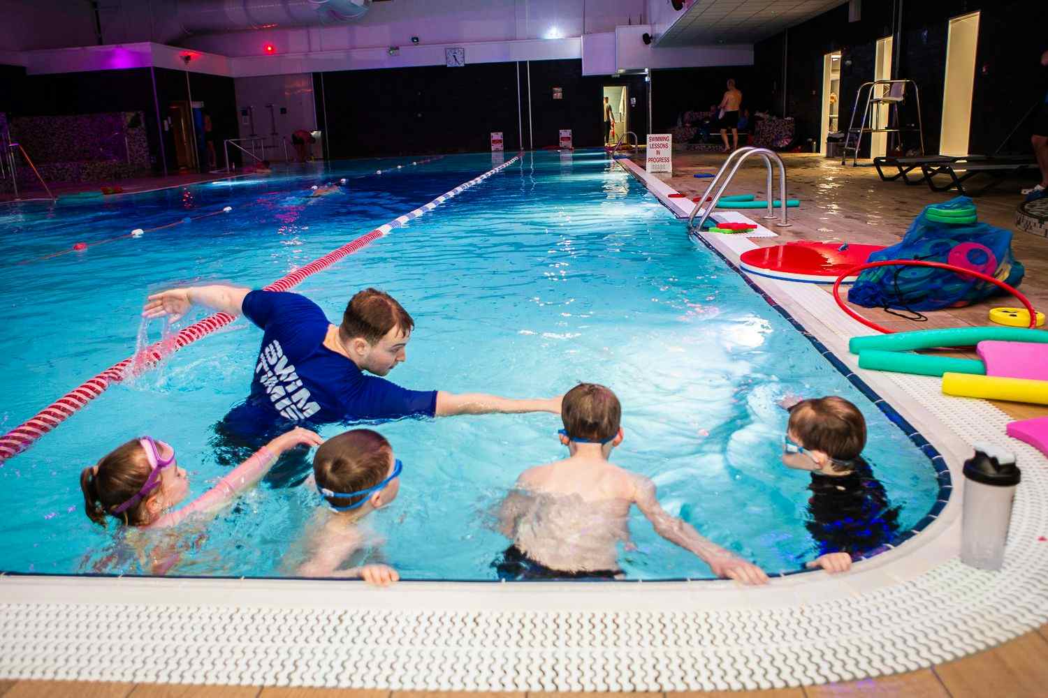Swimming instructor teaching children in pool