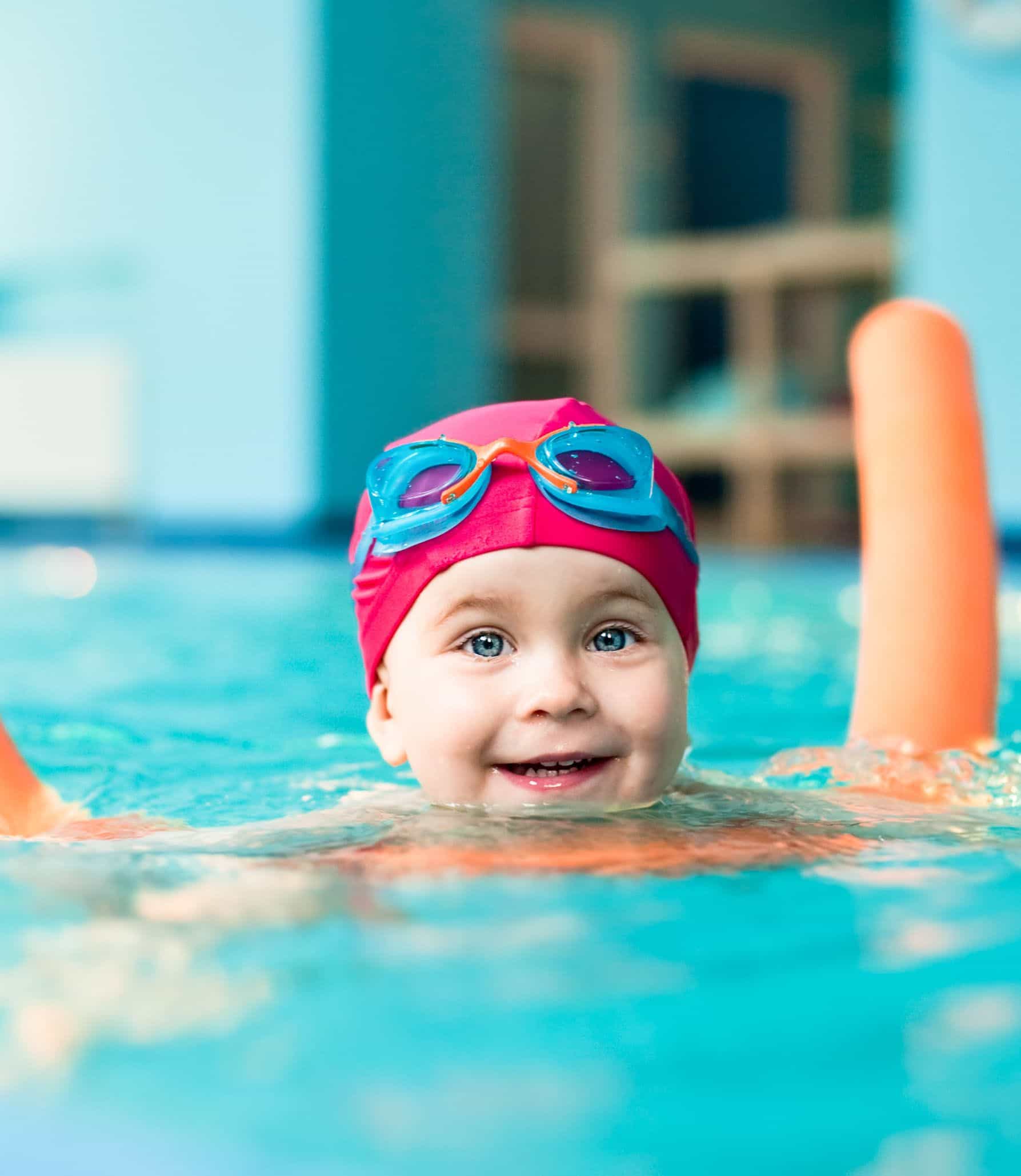 Child swimming in pool with pool noodle