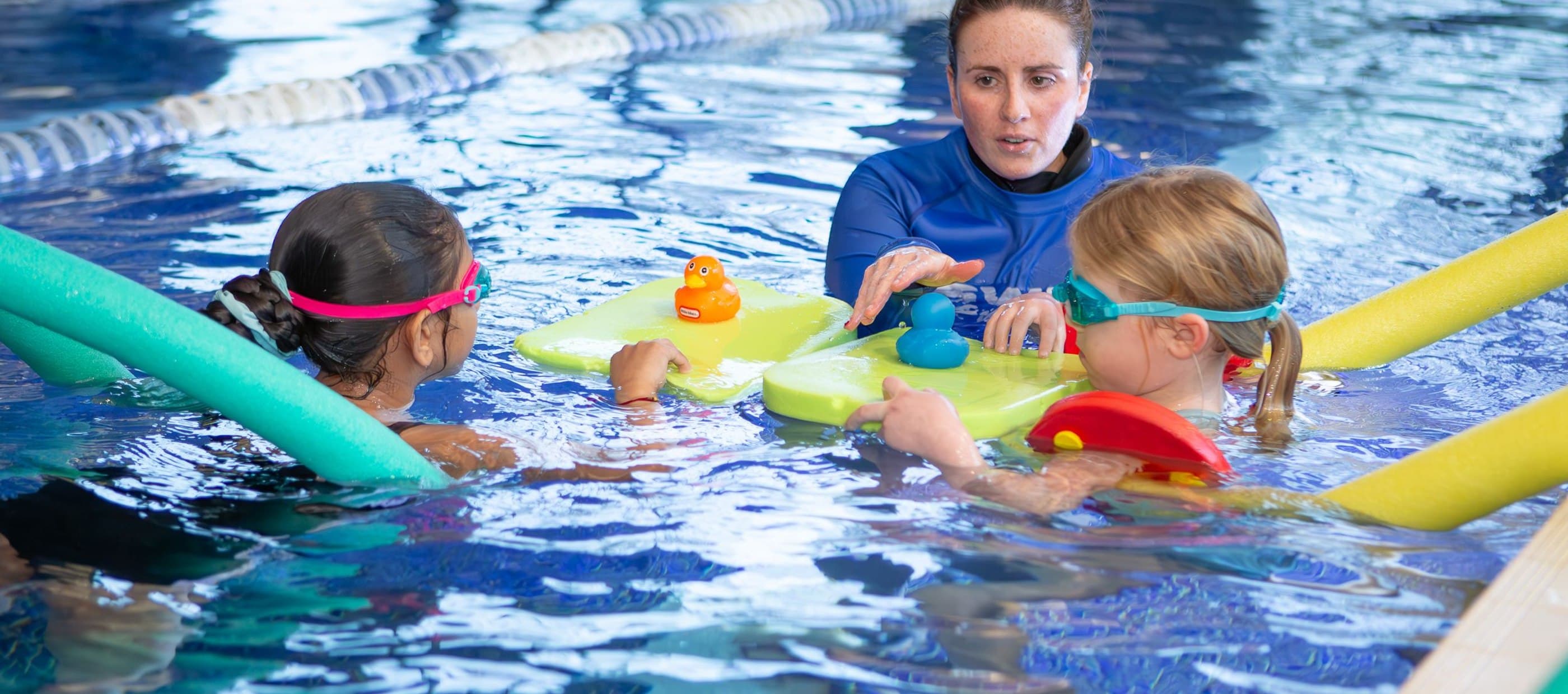 Swimming instructor and children in swimming pool
