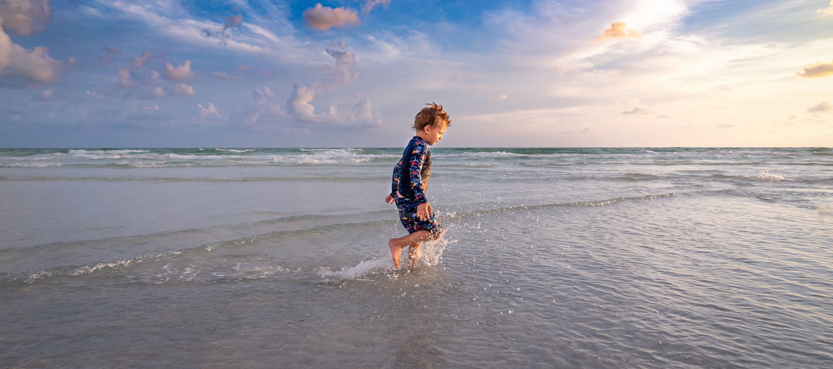 Small child paddling in waves at the seaside.