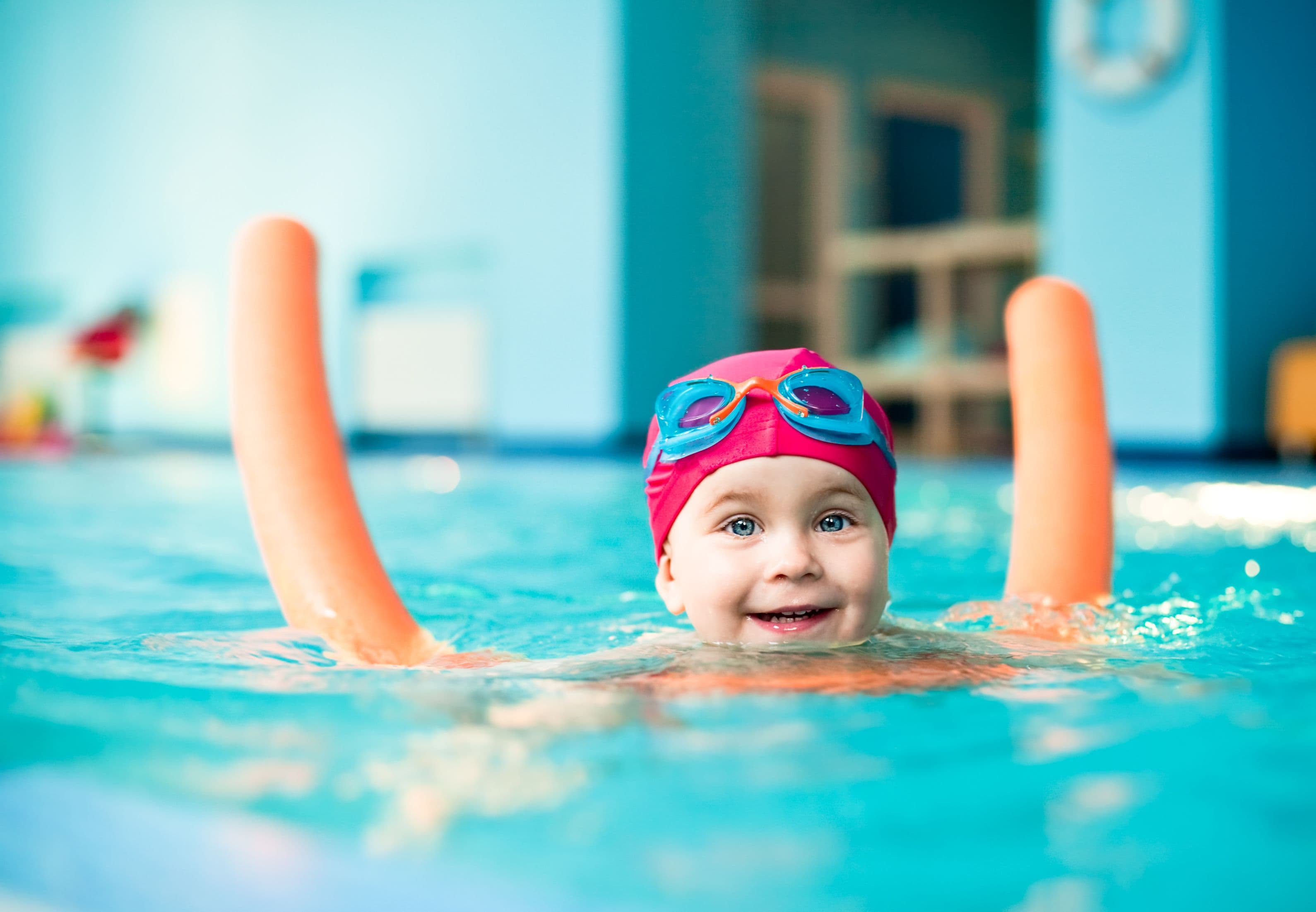 Child swimming in pool with pool noodle